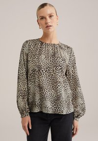 Blus med leopardmönster i lätt tyg, med rund halsringning, långa ärmar med elastiska muddar och en något rynkad nederkant.