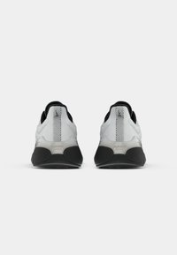 Pantofi atletici albaștri și negri cu un suprafață din plasă, guler căptușit și talpă texturată. Prezintă un design minimalist și accente reflectorizante.