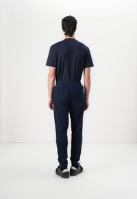 Marineblauwe katoenen t-shirt met korte mouwen en losse fitting marineblauwe sweatpants met een elastische tailleband, gedragen met zwarte platform sneakers.