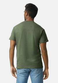 Camiseta verde de manga corta hecha de algodón con escote en cuello redondo. La tela tiene una textura suave y un aspecto ligeramente desgastado.