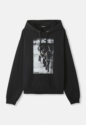 Schwarzer Hoodie aus Baumwolle, mit einem grafischen Druck eines Profils in Grau und Weiß, ausgestattet mit goldfarbener Kordelzug-Hardware.