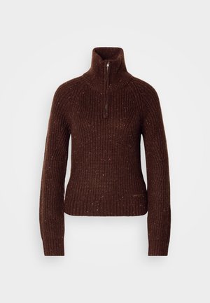 Hnedý pletený sveter s vysokým golierom a polovičným zipsom. Štruktúrovaný vzor s červenými a bielymi bodkami. Slušná silueta.