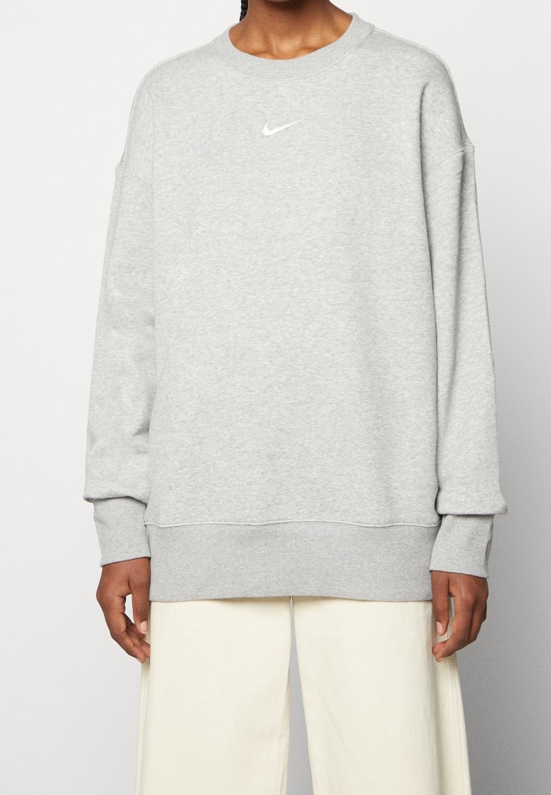 Felpa grigia con scollo rotondo e polsini a costine. Presenta un piccolo logo Nike bianco sul petto. Tessuto morbido con vestibilità comoda.