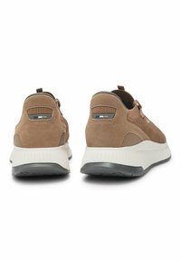 Bruna mockaskor med strukturerad design, vit sula och grå accenter; inkluderar dragöglor och dekorativa sidosdetaljer.