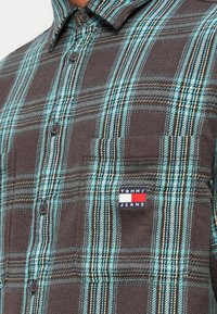 Brun og turkis ternet flannel skjorte med knaplukning, der har en brystlomme og et lille Tommy Jeans logo-patch.