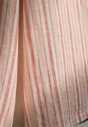 Kerge kangas vertikaalsete triipudega roosa, beeži ja valge toonides, rippumas vabalt nähtava vahega.