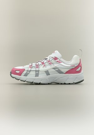 Witte en roze sportschoen met mesh-stof, veters, dikke zool en grijze accenten, getoond vanaf de linkerkant op een neutrale achtergrond.