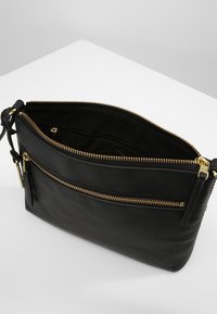 Black leather handbag with a textured finish, featuring multiple zippered compartments and gold-tone hardware accents.