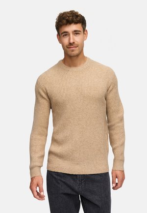 Pullover a coste beige con maniche lunghe e scollo a girocollo, abbinato a jeans in denim scuro, con una consistenza morbida.