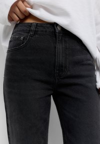 Hoge taille zwarte spijkerbroek van denim met een gladde textuur, voorzien van een knoopsluiting aan de voorkant, riemlussen en een klassiek vijf-pocket ontwerp.
