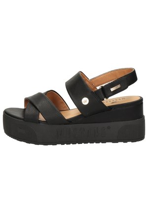 Black platform sandals with two wide cross straps, a back strap, and a textured rubber sole. Features a small metallic accent on the strap.