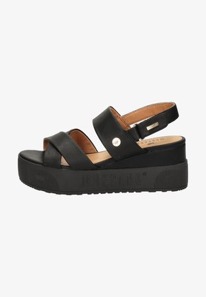 Sandalias de plataforma negras con dos tiras anchas cruzadas, una tira trasera y una suela de goma texturizada. Presentan un pequeño detalle metálico en la tira.
