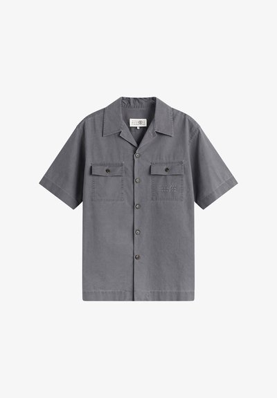 Chemise grise à manches courtes avec deux poches avant à boutons et un col, présentée sur un fond blanc.