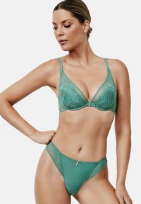 Un soutien-gorge en dentelle turquoise et un string assorti avec un motif floral, dotés de bretelles réglables et d'un détail central discret en métal.