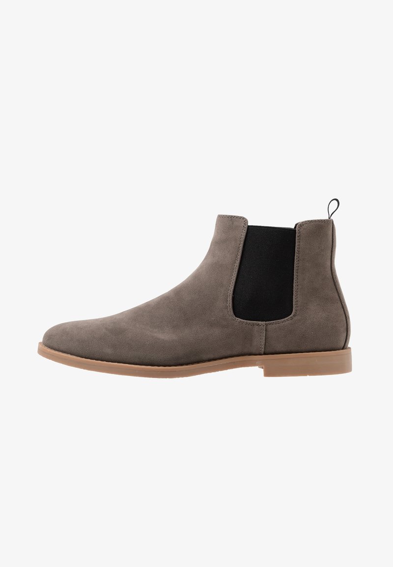 Szare zamszowe buty Chelsea z czarnymi elastycznymi panelami po bokach, zaokrąglonym noskiem i jasnobrązową gumową podeszwą. Posiadają pętelkę z tyłu.