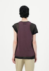 Donkerpaarse mouwloze top met een transparante zwarte mesh laag op de schouders en een ronde halslijn. Label zichtbaar aan de achterkant.