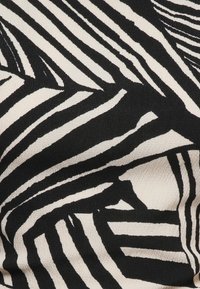 Tissu imprimé zèbre noir et blanc avec des rayures irrégulières, audacieuses et une surface légèrement texturée.
