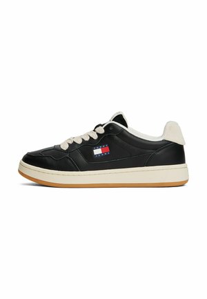 Zwarte leren sneakers met crèmekleurige accenten, voorzien van ronde veters, een dikke witte tussenzool en een klein merklogo in rood en blauw.