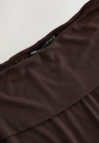 Brown high-waisted full-length leggings made of ribbed fabric, featuring a smooth waistband and no visible hardware or patterns.