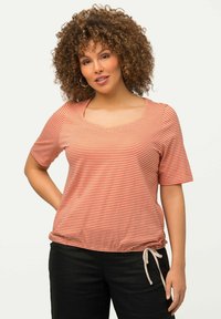 Camiseta de manga corta a rayas rojas y blancas con escote en forma de barco, dobladillo fruncido y detalles de cordón. Tela suave, corte relajado.