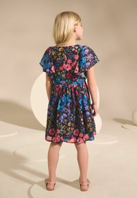 Lilleline kleit, millel on tumesinine taust, lühikesed lehvikvarrukad, elastne vöökoht ja põlveni ulatuv seelik mitmevärviliste lilledega.