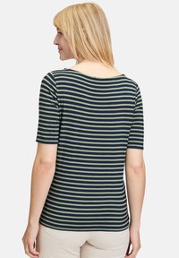 Pasiasta koszulka z krótkim rękawem w kolorze granatowym i oliwkowym, z okrągłym dekoltem i miękkim, gładkim materiałem. Kroju sięgająca poniżej talii.