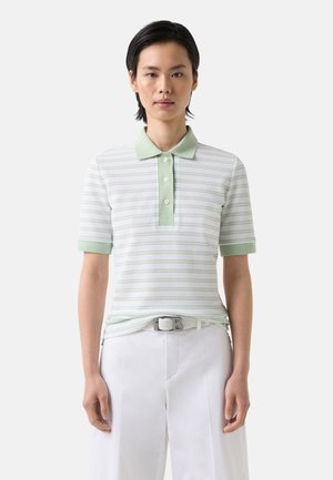 Polo shirt in lichtgroen met horizontale strepen, korte mouwen en een drie-knopen-gemakkelijk. Gecombineerd met witte broek en een gevlochten riem.