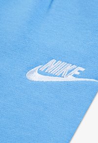 Μπλε βαμβακερό ύφασμα με κεντημένο λευκό λογότυπο Nike σε καμπυλωτό σχέδιο και υφασμένο μοτίβο.