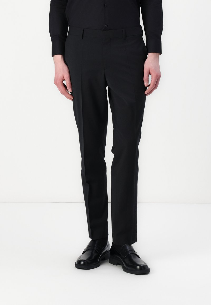 Mustat räätälöidyt housut slim fit -mallissa, joissa on litteä etuosa, vyölenkit ja tyylikäs kangas, yhdistettynä kiiltäviin mustiin kenkiin.