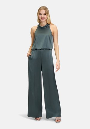 Tuta senza maniche in satin verde scuro, con scollo a cowl e silhouette a gamba larga; presenta una vita arricciata e tasche laterali.