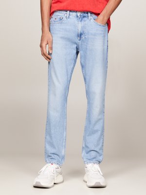 Lyseblå denimjeans med rett ben, fem lommer og subtil falming. Kombinert med hvite sneakers og en rød skjorte.