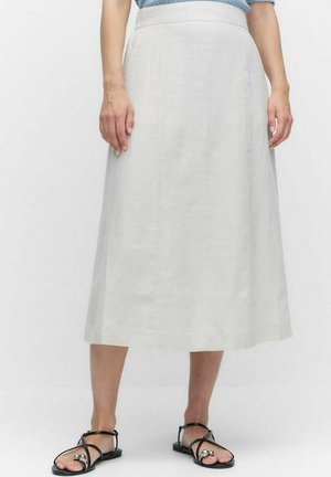 Jupe légère gris clair, arrivant au genou, en lin avec une texture lisse, présentant une coupe droite et de subtils détails sur les coutures latérales. Portée avec des sandales noires.