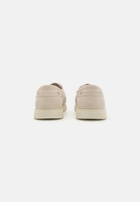 Zapatos de ante beige con un perfil bajo y detalles texturizados en los laterales, que cuentan con una suela contrastante para mayor agarre y durabilidad.