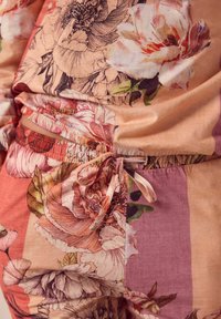 Set de loungewear cu model floral, cu o textură moale și ușoară. Are un talie cu șnur și o combinație de nuanțe piersică și roz.