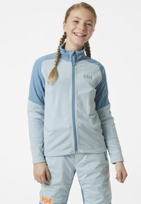Jasnoniebieska polarowa kurtka z pełnym zamkiem błyskawicznym, wysokim kołnierzem i sportowym fasonem. Z kontrastowymi niebieskimi akcentami i logo na piersi.