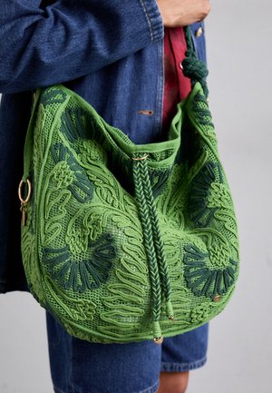 Grüne Häkelhandtasche mit filigranen, erhabenen Mustern, geflochtenem Kordelzugverschluss und metallischen Akzenten. Weiche Textur und große Hobo-Form.