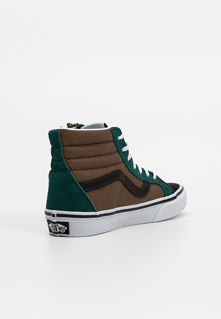 Baskets montantes en daim vert et marron avec lacets blancs, accents noirs, semelle en caoutchouc blanche et logo Vans au niveau du talon. Panneaux texturés.