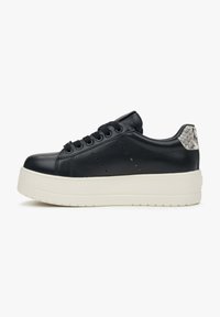 Zwarte leren sneaker met een dikke witte plateauzool, een gestructureerde grijze accent aan de hiel en decoratieve perforaties langs de zijkanten.