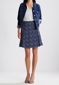Denim jacket with light blue buttons, mint green blouse, and flared navy floral skirt. Gray heels complete the outfit.