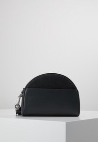 Svart läder- och mockaväska i halvmåneform, med en silverkedjesnor, släta och strukturerade ytor, minimalistisk design utan mönster.