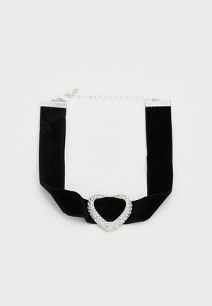 Choker en velours noir avec un centre en forme de cœur orné de strass et une quincaillerie en argent, doté d'une chaîne réglable.