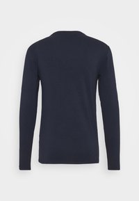 Chemise à manches longues bleu marine avec col rond, fabriquée en tissu doux. Présente un design simple et épuré sans motifs ni ornements visibles.