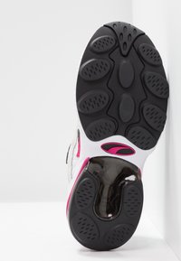 Suola della scarpa in gomma nera con motivo di battistrada circolare, con accenti bianchi e rosa; superficie testurizzata per presa e stabilità.