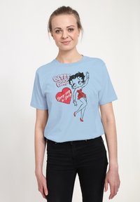Camiseta de algodón azul claro con un gráfico de Betty Boop, acentos en rojo en forma de corazón y un texto juguetón "Beep-op a Deop" en una fuente en negrita.