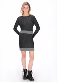 Vestido de punto negro con rayas horizontales grises, diseño ajustado, mangas largas y textura acanalada; combinado con botines negros con cordones.