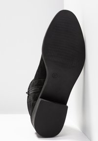 Bottine noire à semelle texturée, petit talon bloc, fermeture éclair latérale, taille 37 indiquée sur la semelle, présentée sur fond blanc.