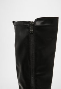 Schwarze Lederstiefel bis zum Knie mit einem seitlichen Reißverschluss, glatter Textur und gestickten Akzenten an der Oberseite.