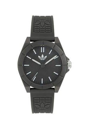 Mustan analoogkellaga, millel on tekstureeritud kummist rihm, ümmargune korpus ja kolm hõbedast kätt. Rihmal on reljeefne logo.