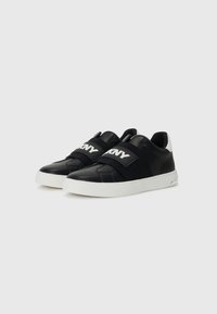 Baskets noires avec un dessus en cuir lisse, une sangle élastique avec le logo 'DKNY', une semelle en caoutchouc blanche et une cheville rembourrée pour le soutien.