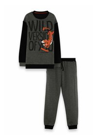 Donkergrijze en zwarte pyjama set voor kinderen met tijger op skateboard en de tekst "WILD VERSION OF YOU" op het sweatshirt.